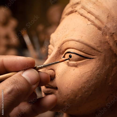 Sculptor carefully paints the eye of a clay Durga goddess during creation