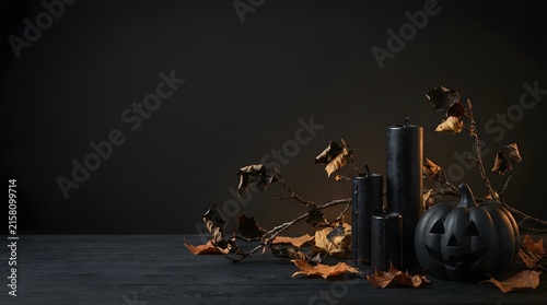 Festive halloween composition featuring small black pumpkins and golden autumn leaves arranged on a dark rustic wooden background