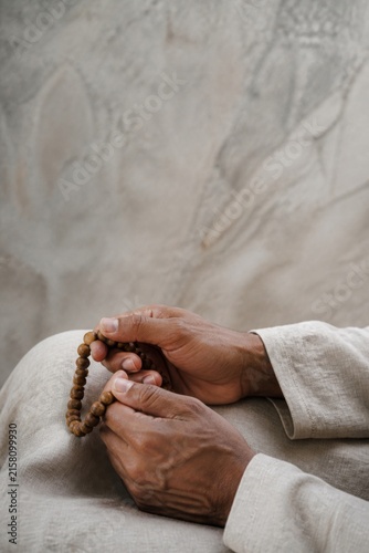 Close-up of an African American man holding wooden prayer beads in quiet meditation. Spiritual reflection, faith, mindfulness, and religious devotion concept with copy space.