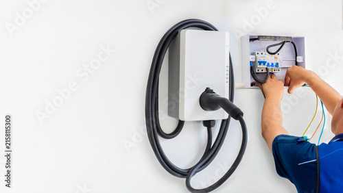 Foto Electrician installing EV wall box charger and residential breaker panel on whit