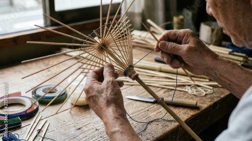 Elderly artisan carefully crafts a traditional bamboo umbrella frame by hand.