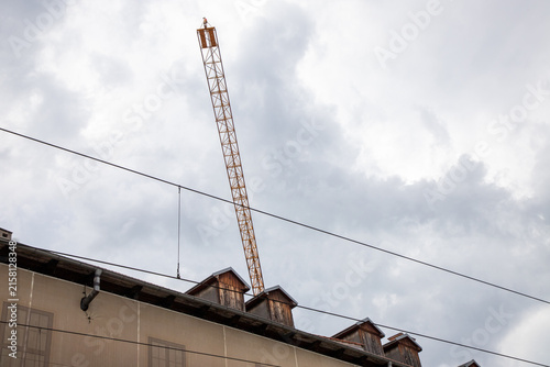 Принти на полотні Luffing jib tower crane, positioned tightly between urban buildings, its movable angled steeply upward to operate within confined airspace constraints