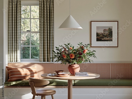 Bright breakfast nook featuring built-in bench seating with patterned cushions, round table, and floral centerpiece, complemented by natural light from large window