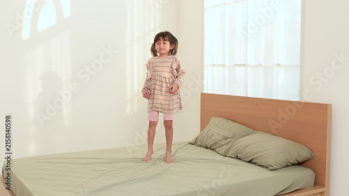 Girl Jumps on Bed in Bright Room During Afternoon Playtime