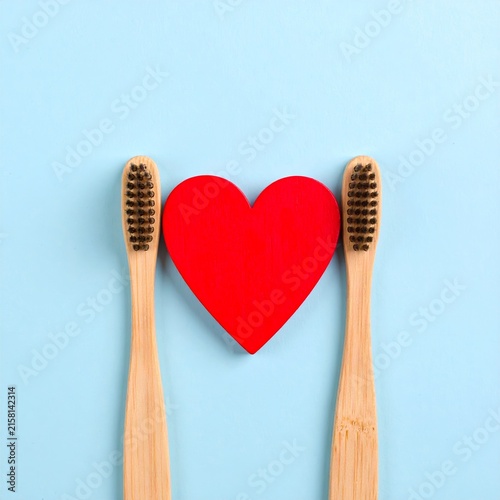 two wooden tooth brushes with a red heart on a blue background