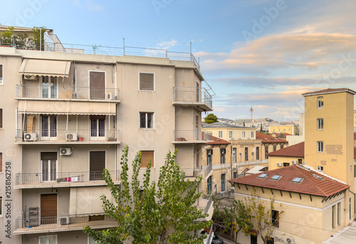 Fotografie Residential apartment buildings and tiled rooftops beneath evening clouds in Kol