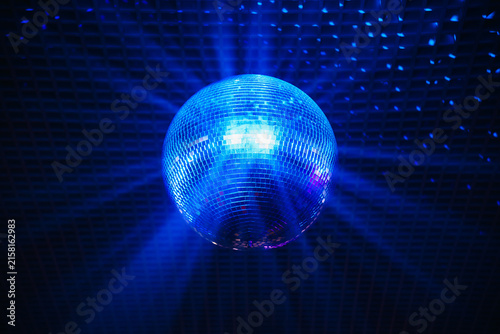 disco ball with mirror surface and bright rays, blue light, hanging on ceiling, night party background