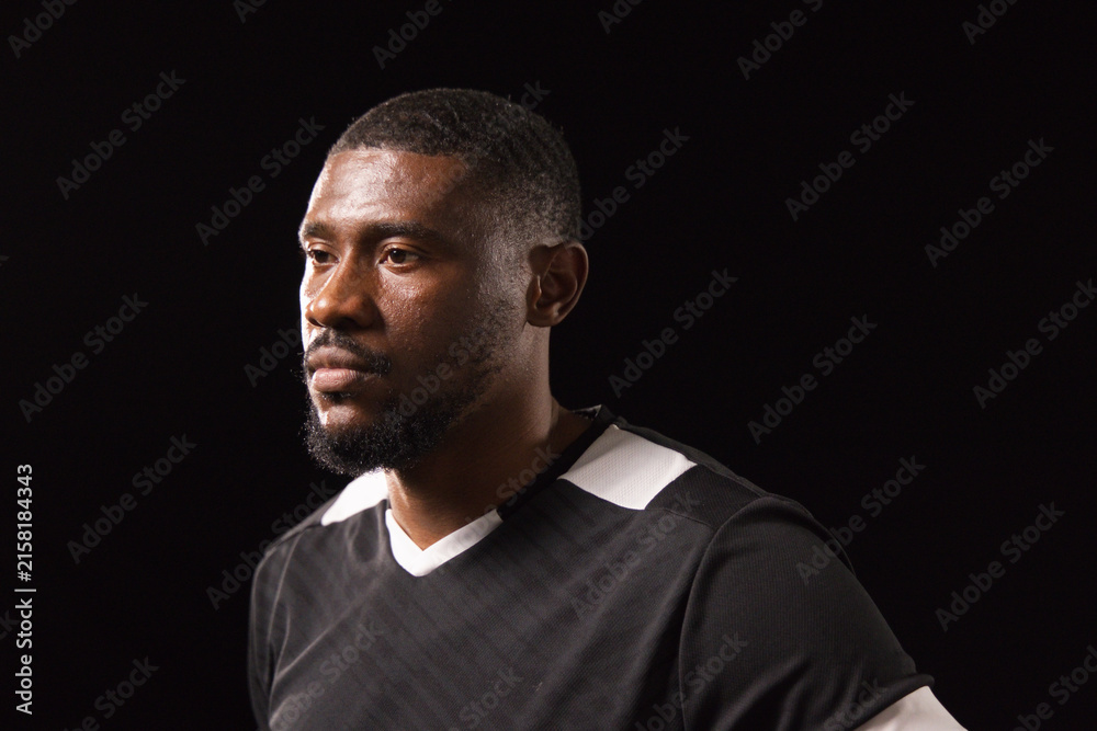 Obraz premium African man posing under studio lighting wearing black athletic shirt with white trim