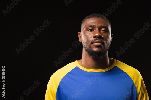 Fotografie Man posing in studio, wearing blue and yellow raglan shirt under dramatic direct