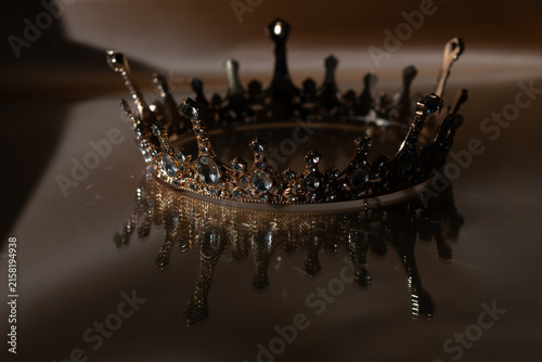 Luxury Golden Crown with Crystal Details and Reflection on Brown Background. Royal Elegance.