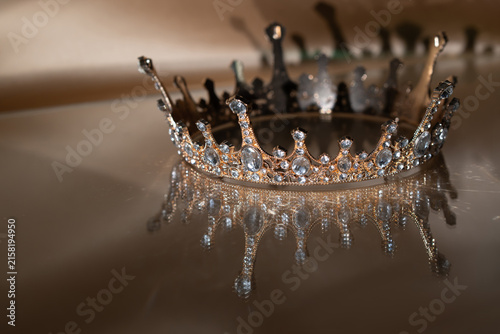 Luxury Golden Crown with Crystal Details and Reflection on Brown Background. Royal Elegance.
