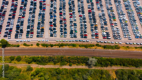 Obraz na plátně Cars parked in a large lot next to train tracks in the daytime