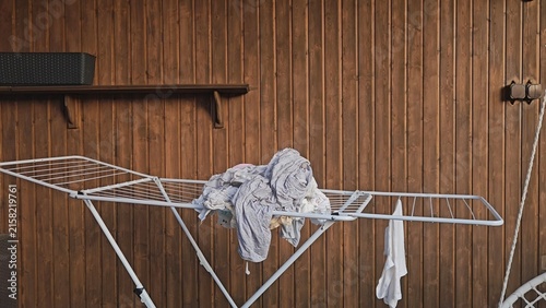 Konstfotografi A white metal drying rack holds a crumpled grey garment and a small white cloth