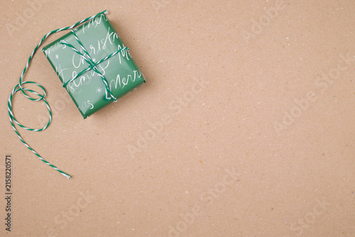 Canvastavla Minimal Christmas composition featuring a green wrapped gift tied with decorative twine on a warm beige background with generous copy space