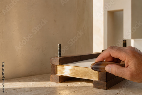 Bookbinder Hand Burnishing Gilded Book Edge in Desert Studio with Copy Space