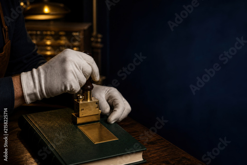 Bookbinder Hands Applying Gold Foil Tooling to Book Cover with Copy Space