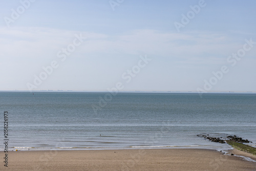 Calm wide sandy beach meeting the tranquil sea waters under a clear sky in Westende - Belgium