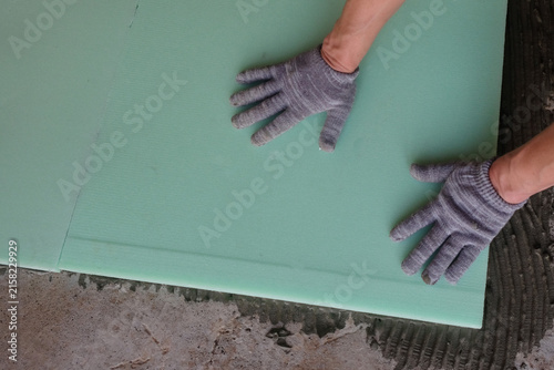 Fotografie Floor insulation: a specialist glues polystyrene foam boards to a concrete scree