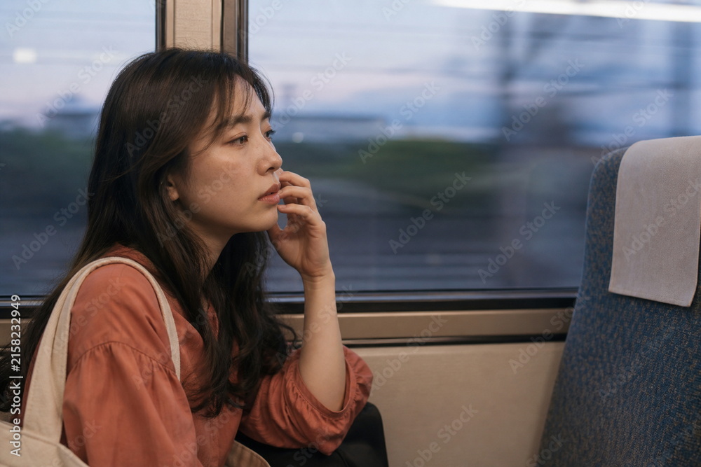 Fototapeta premium 夕方の電車内で頬に触れる女性の横顔