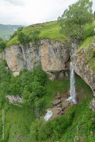 Powerful waterfall cascades down rugged cliff amid lush greenery