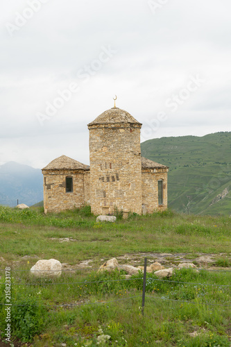 Ancient stone structure with domed roof stands amid rolling green hills