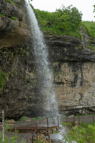 Powerful waterfall cascades down rugged cliff amid lush greenery