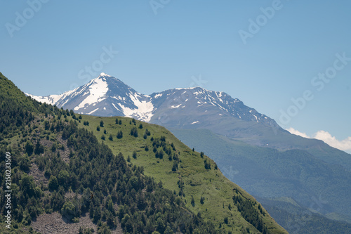 Majestic snow-capped mountains rise above rolling green hills