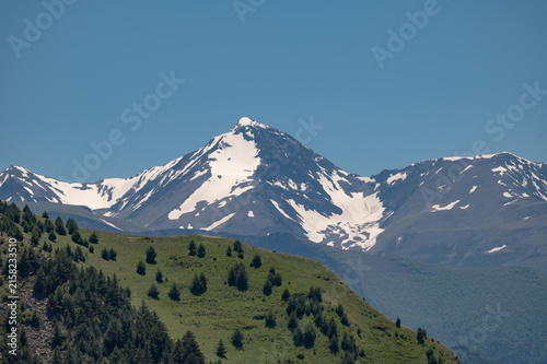 Majestic snow-capped mountains rise above rolling green hills