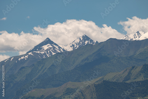 Majestic snow-capped mountains rise above rolling green hills