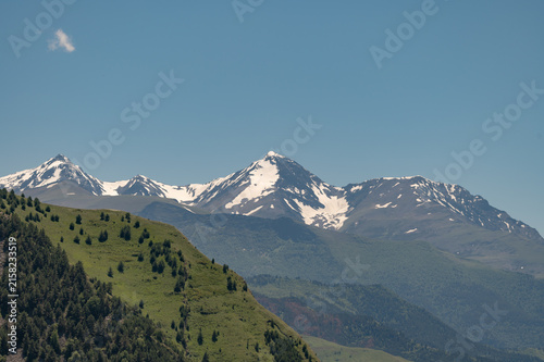 Majestic snow-capped mountains rise above rolling green hills