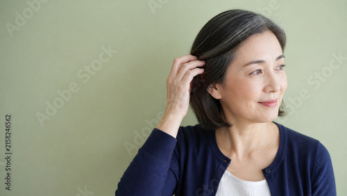 Naklejka ヘアケア 髪に触れる日本人女性 50代と余白のある背景