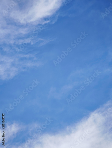 Vertical clear blue sky with soft white cirrus clouds background