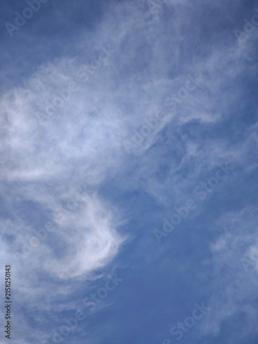 Vertical view of bright blue sky with wispy clouds and copy space