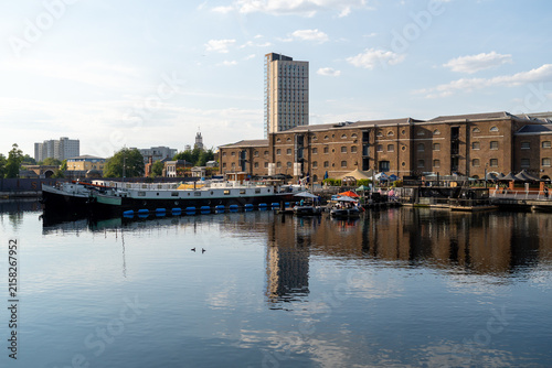 Canvas Print Calm Urban Waterfront with Boat and Modern Buildings Reflecting in Water on a Su
