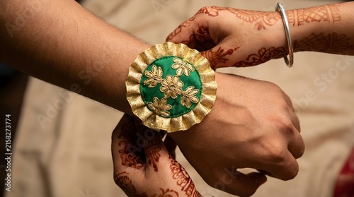 A close-up shot of a woman tying a rakhi on her brother's wrist, symbolizing their bond.