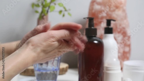 Woman performing a relaxing hand and wrist self massaging as part of a wellness and selfcare routine at home. Female applying cream from tube to care moisturizing her palms skin