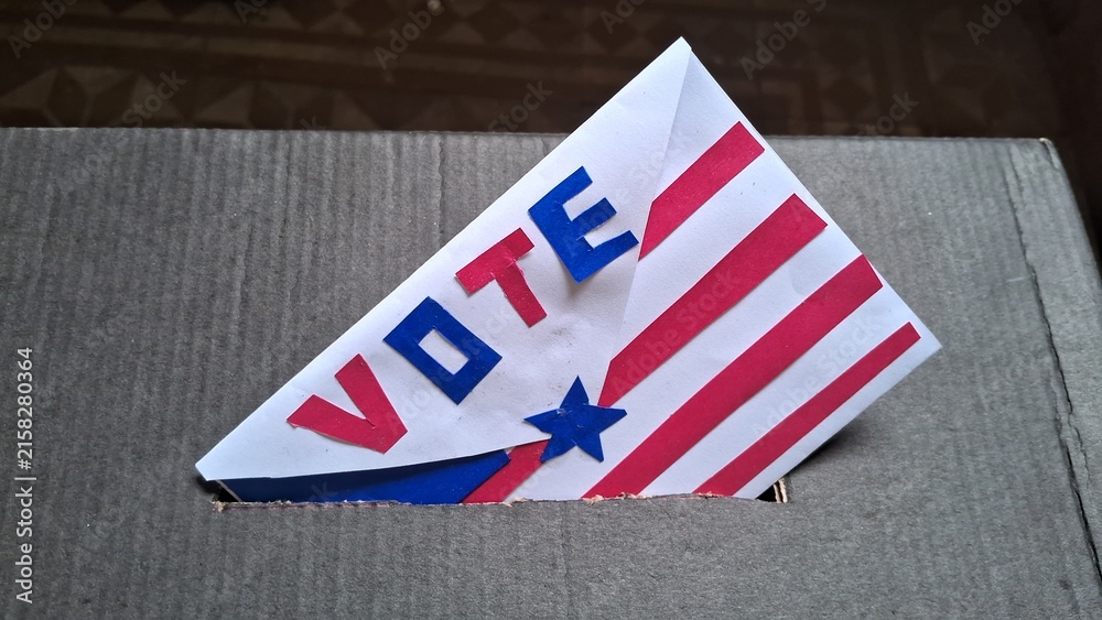 Obraz premium Decorative patriotic ballot envelope inserted into a simple cardboard voting box