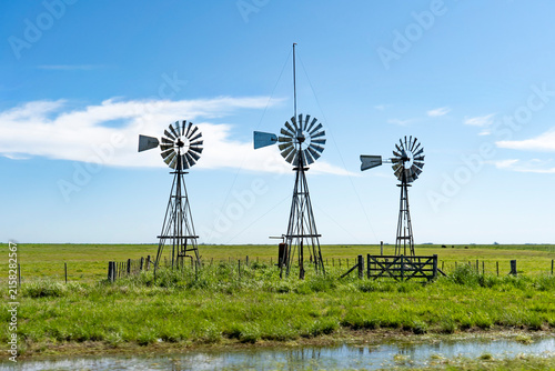 Three vintage windmills standing in green agricultural field in Argentine