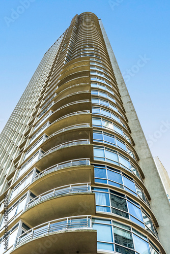 Contemporary curved glass tower architecture rising towards blue sky