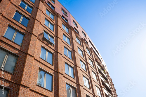 Low angle view of modern red brick residential building facade against blue sky