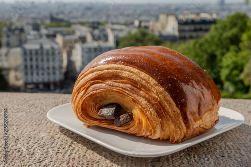 French pastry roll pain au chocolat for traditional breakfast, fresh baked in artinasal bakery in Paris, France, view from Montmartre and Basilica Sacre-Coeur to central Paris
