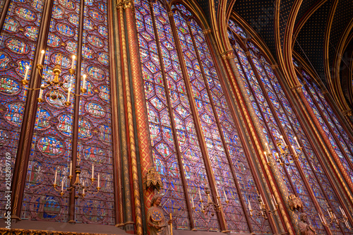 Fotografie Interior view of medieval Gothic cathedral featuring towering stained-glass windows that fill nave with colored light, detailed biblical iconography