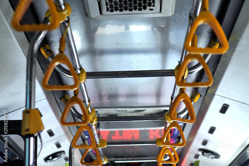 Yellow Hand Grips And Stainless Handrails On Public Bus Ceiling Interior During Urban Commute