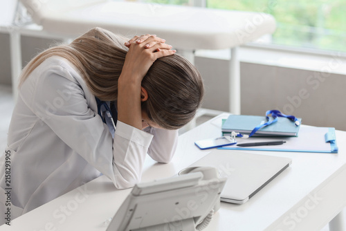 фотографія Overworked female doctor experiencing burnout and stress, head in hands at a hos