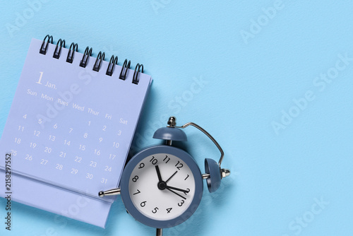 Calendar with alarm clock on blue background