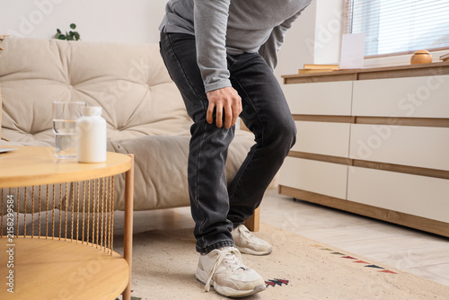 Mature man suffering from knee pain at home