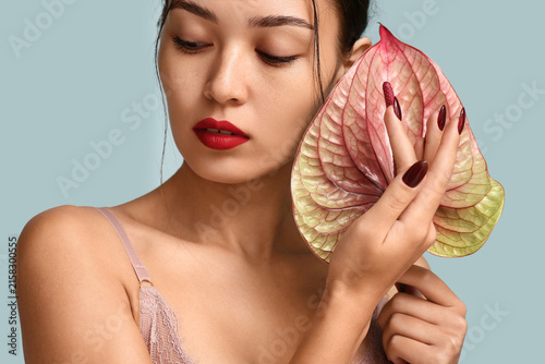 Sexy Asian woman with beautiful anthurium flower on color background. Erotic ...