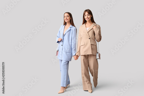 Beautiful young twin sisters on grey background