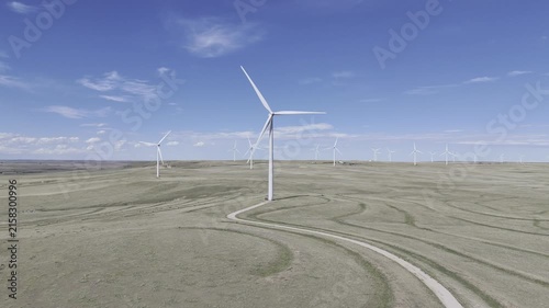 Wind turbines on wind farm in southern Colorado. Aerial drone footage pushing in towards a large wind turbine rotating in the wind on a sunny day in the southwest United States.