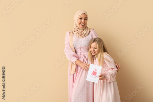Beautiful young Muslim woman and her cute little daughter with greeting card ...